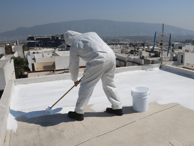 A man paints the roof of a building with a brush