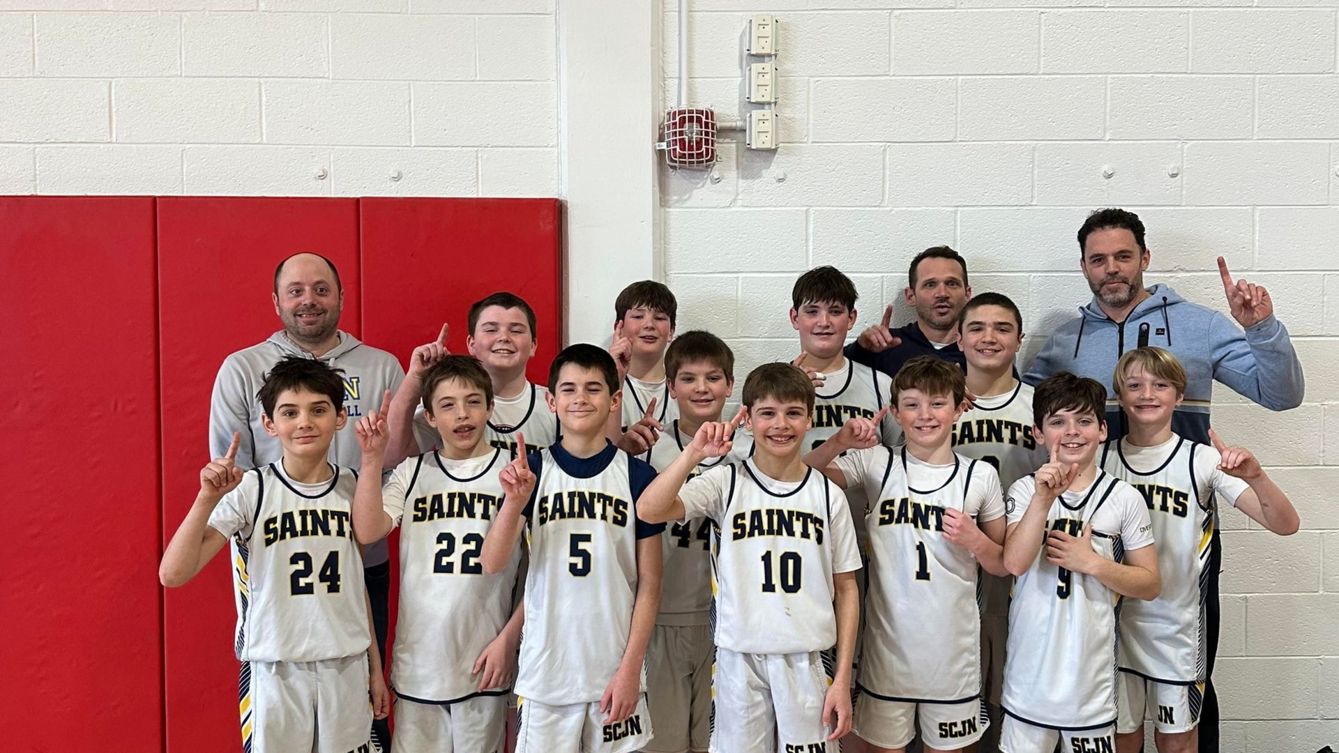 JV Boys Basketball Team celebrating their Region 32 Championship victory with a gold trophy.