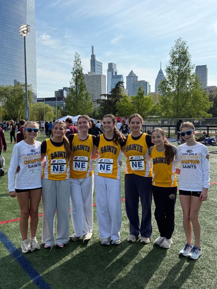 Group of runners posing on a track with a city skyline in the background, wearing yellow and white shirts