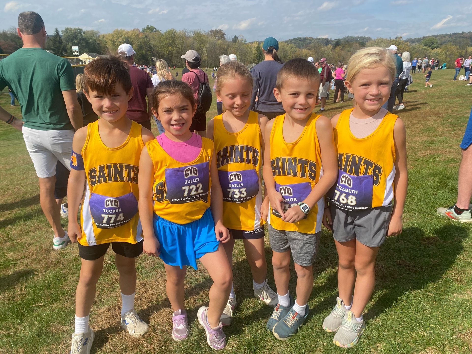 Five children in yellow jerseys posing outdoors before a cross-country race