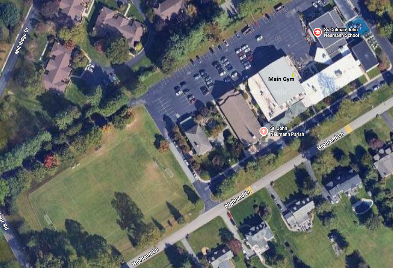Aerial view of a sports complex with football fields, a running track, pool, and large buildings.