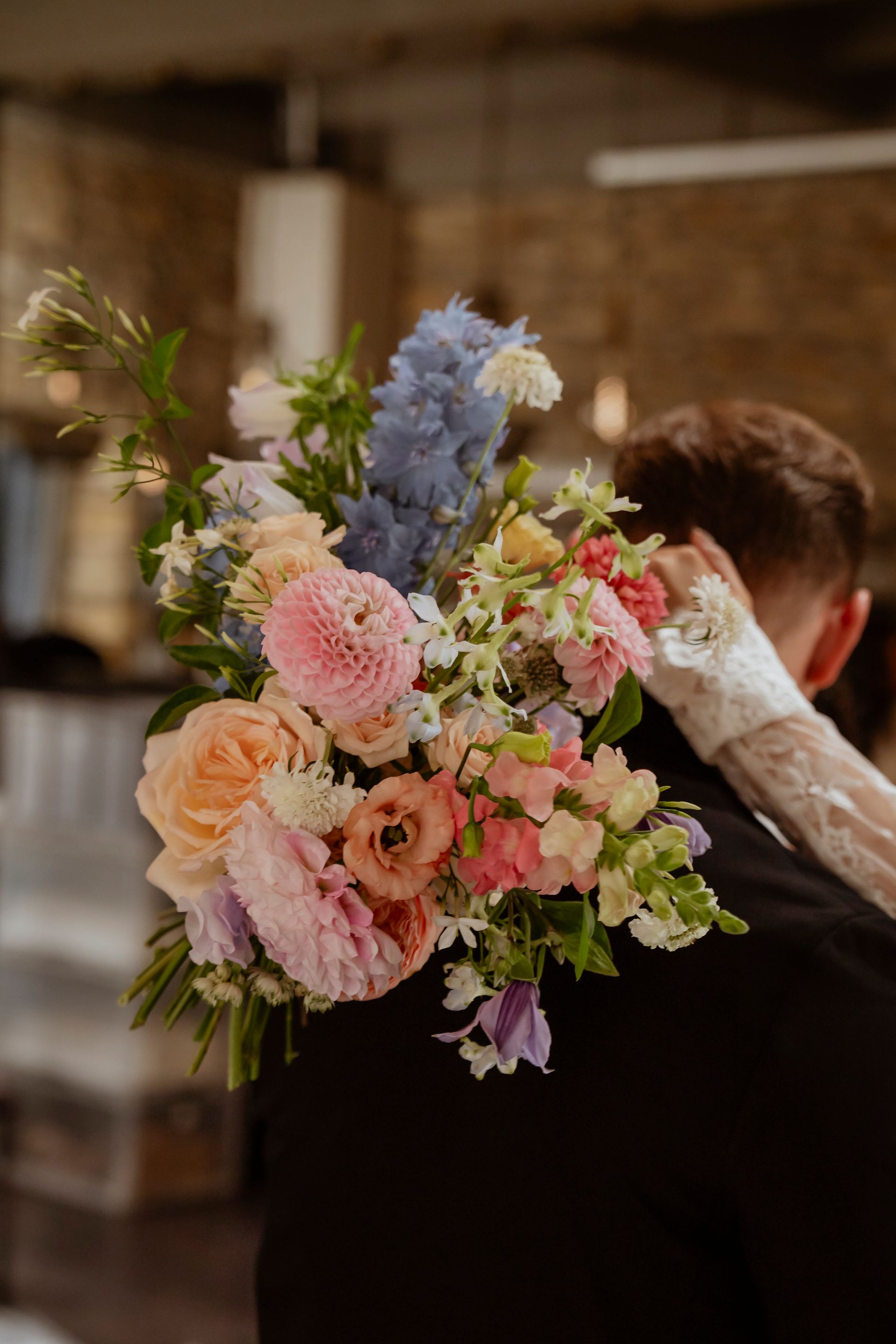 A bride is holding a bouquet of flowers on her groom 's back.