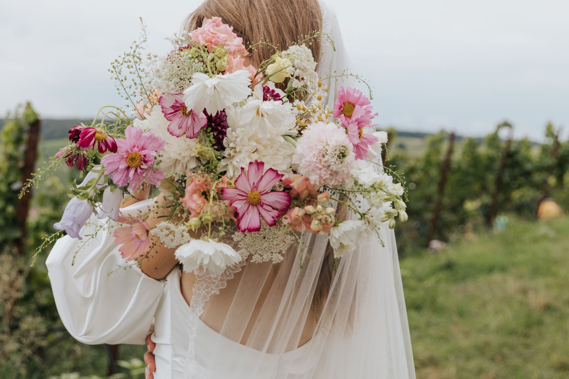 The bride is holding a bouquet of flowers in front of her face.