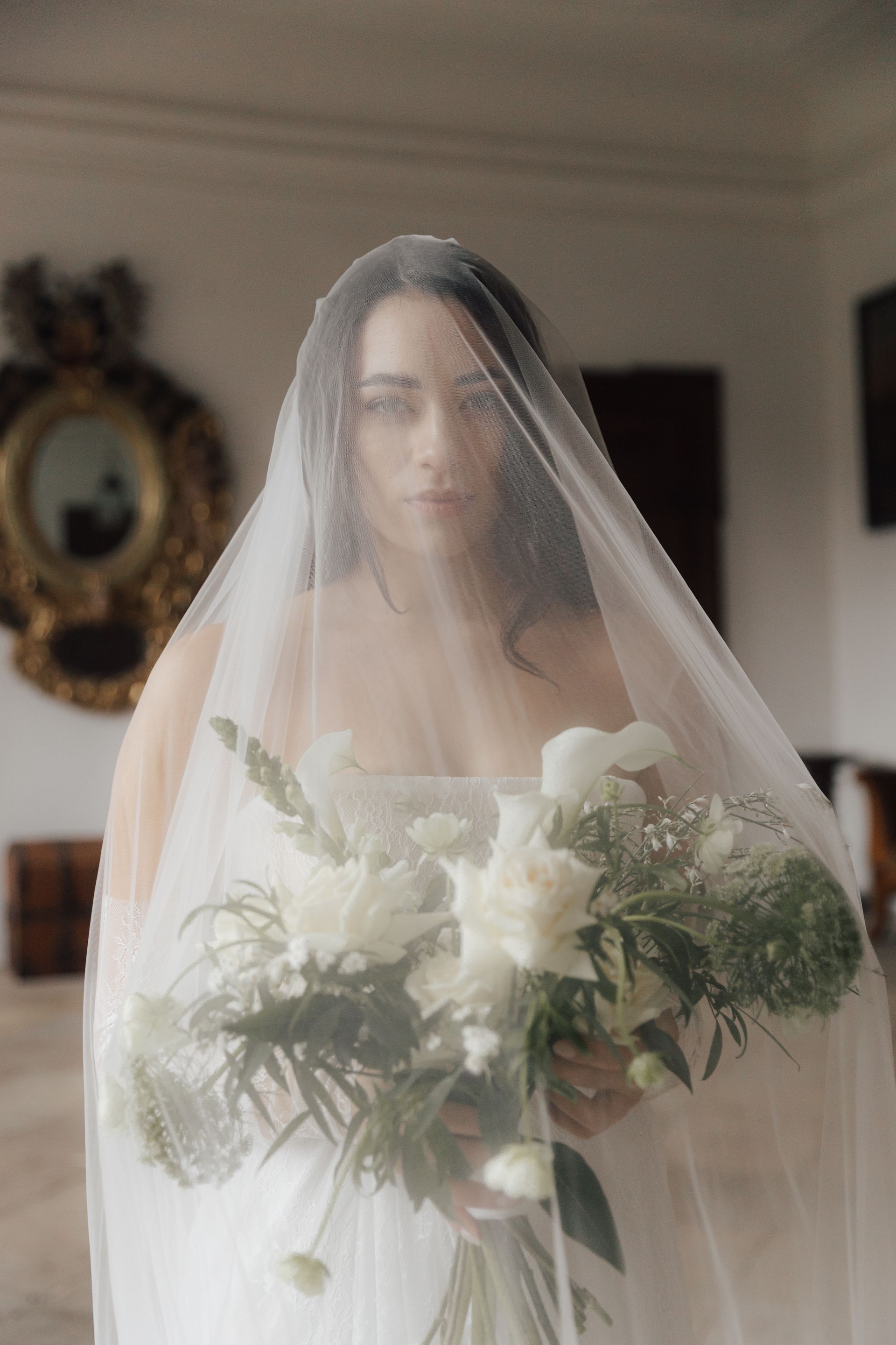 The bride is wearing a veil and holding a bouquet of flowers.