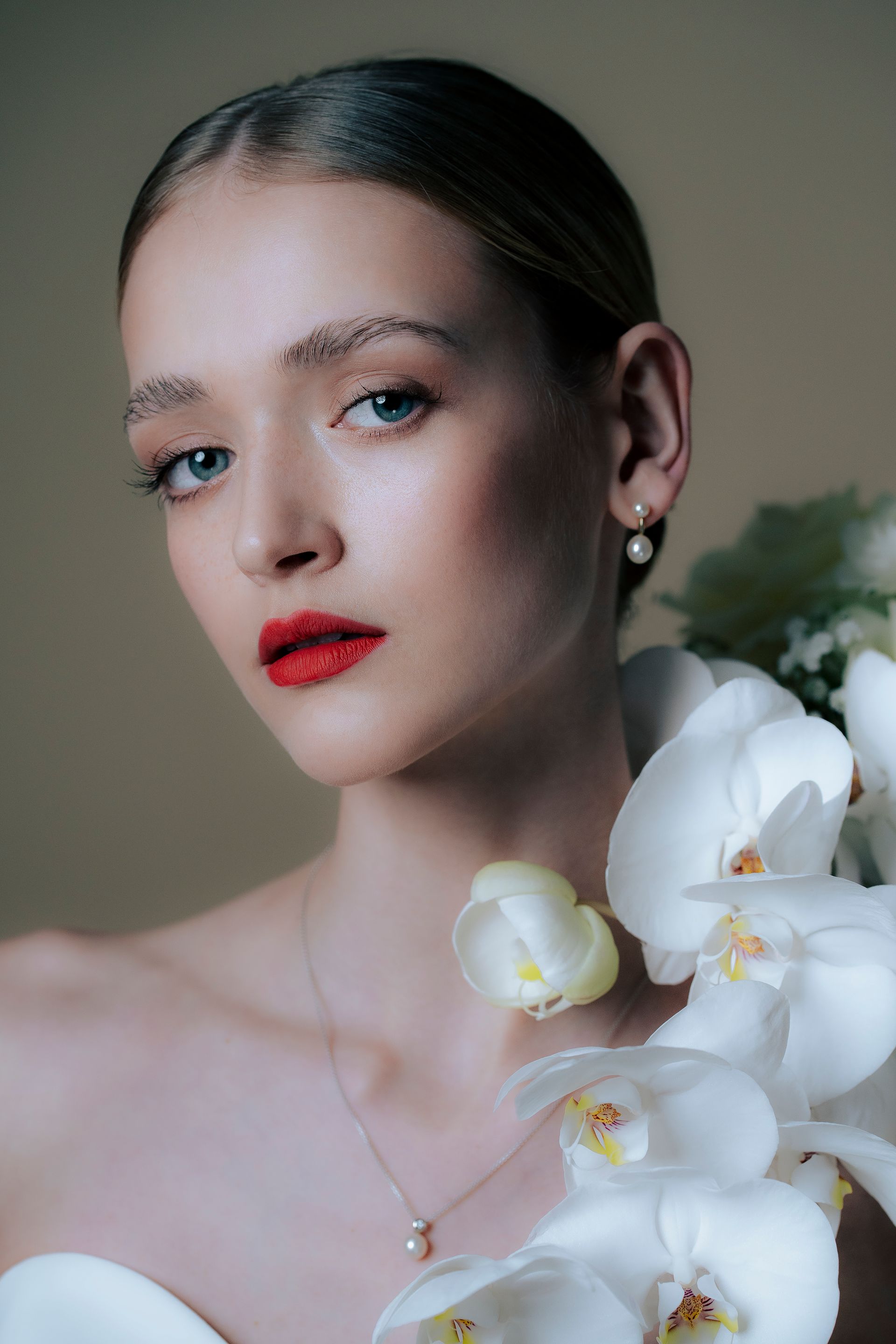 A woman in a wedding dress is holding a bouquet of white orchids.
