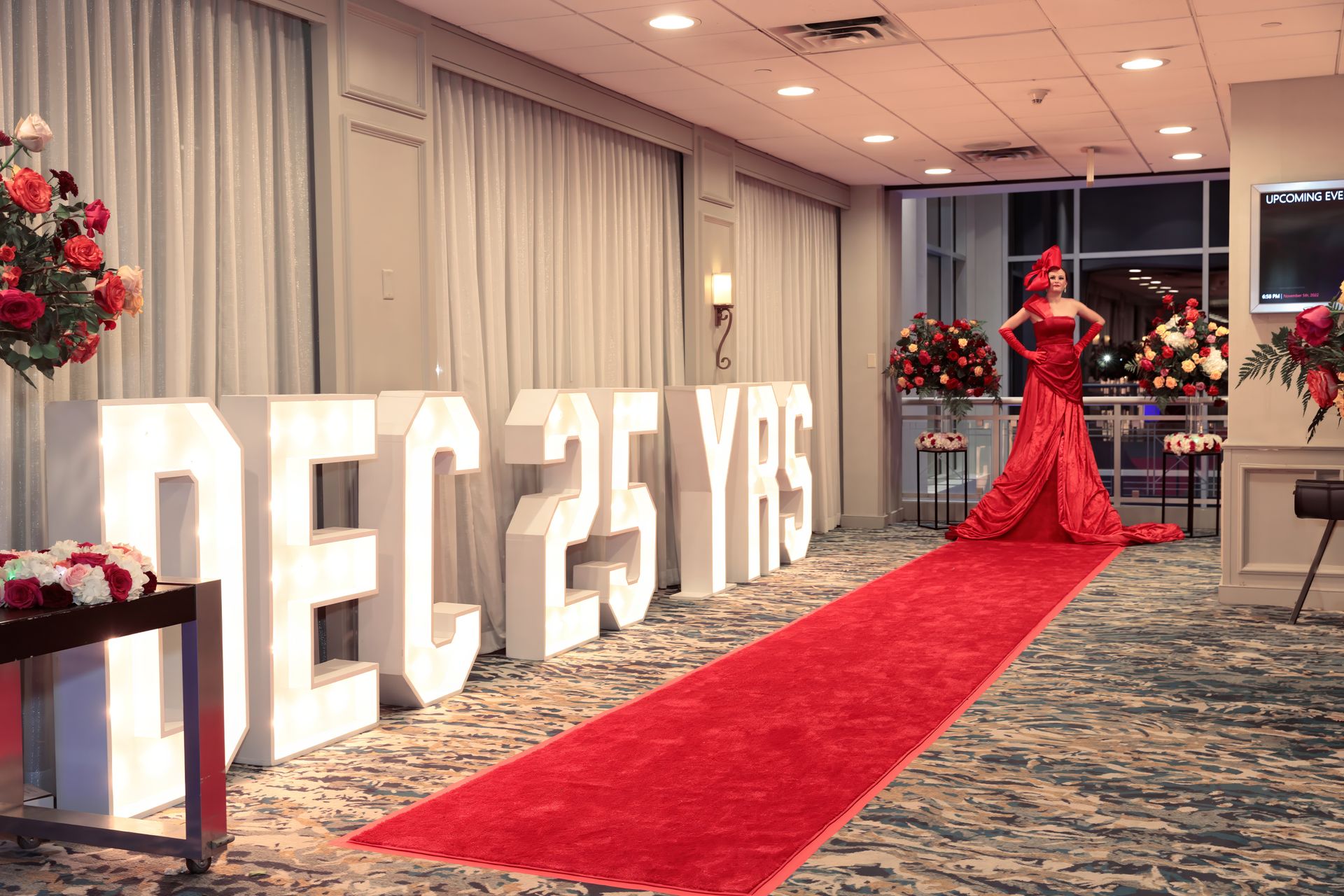 A woman in a red dress is walking down a red carpet.
