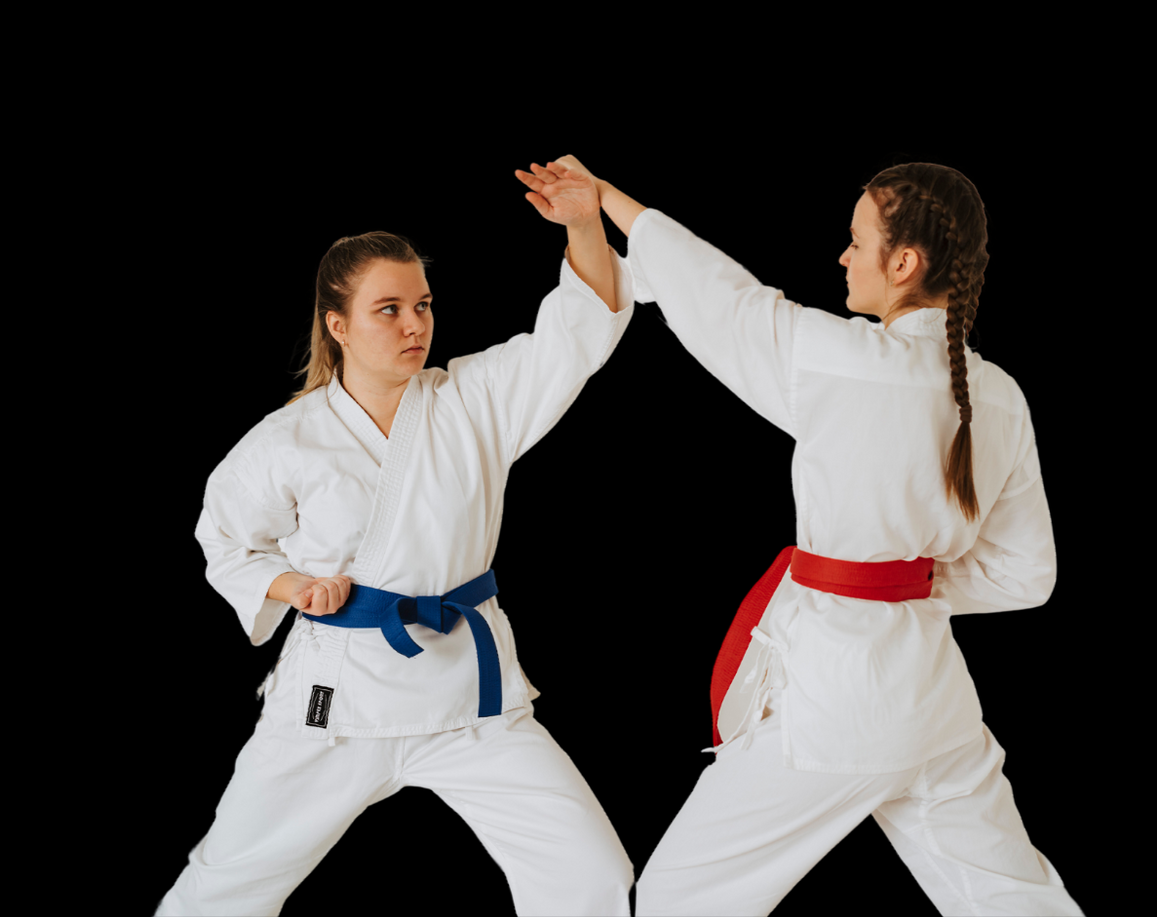 Two women in karate uniforms are giving each other a high five.