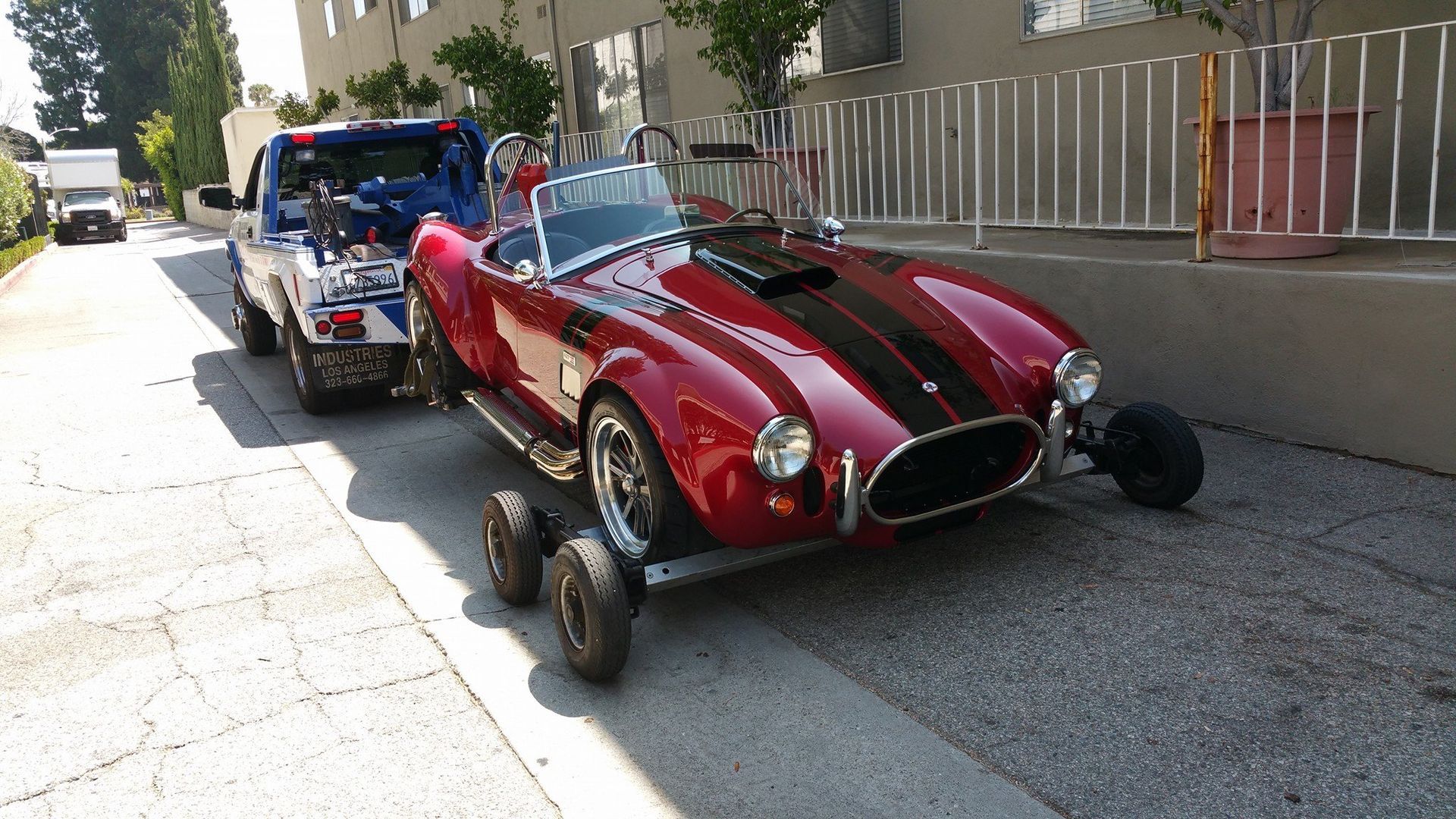 A red sports car is being towed by a tow truck