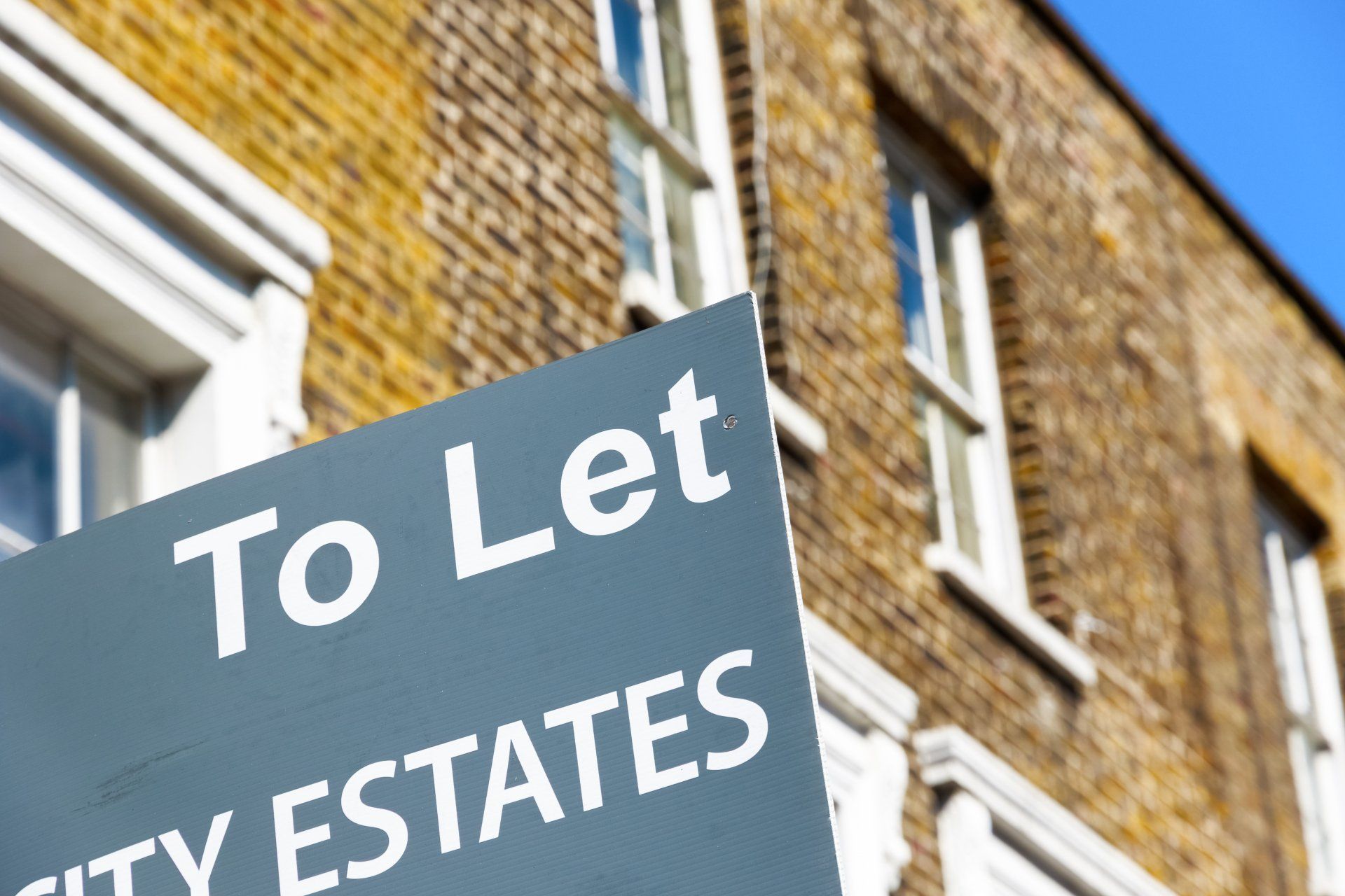 A to let sign in front of a brick building