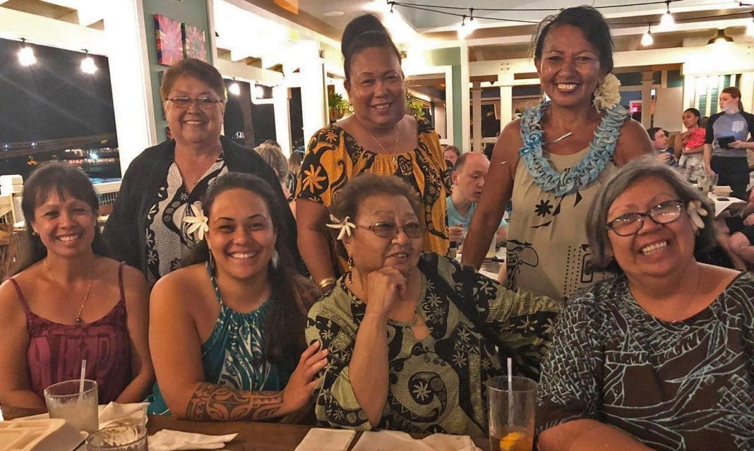 A group of women are posing for a picture while sitting at a table.