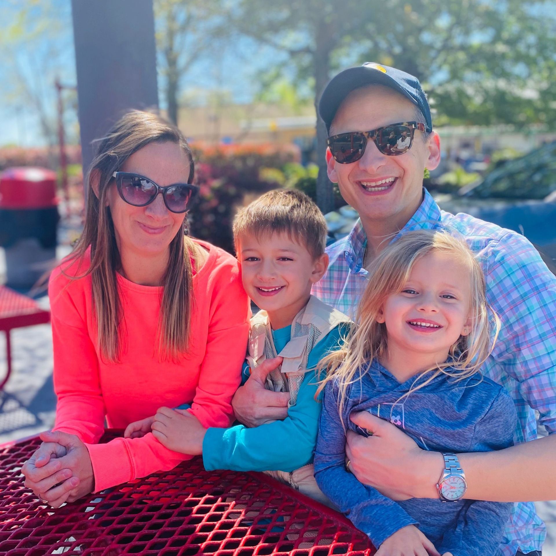 Dr. Lori Porras of Little Waves Pediatric Dentistry is posing for a picture while sitting at a picnic table with her family.