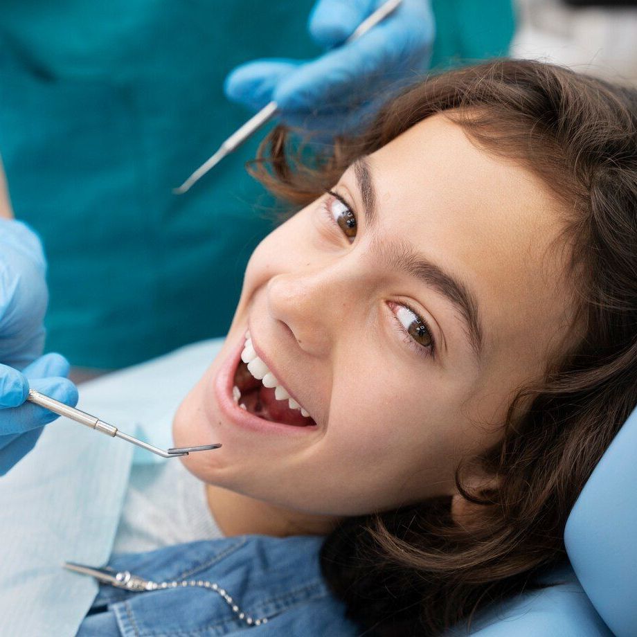 A young girl is having her teeth examined by a dentist.
