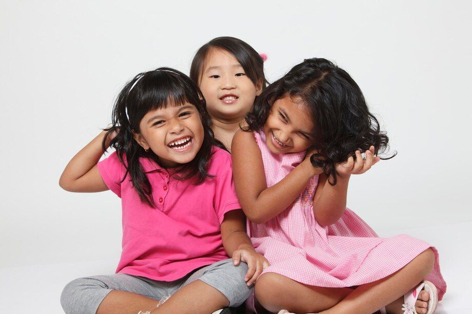 Three little girls are sitting on the floor and smiling for the camera
