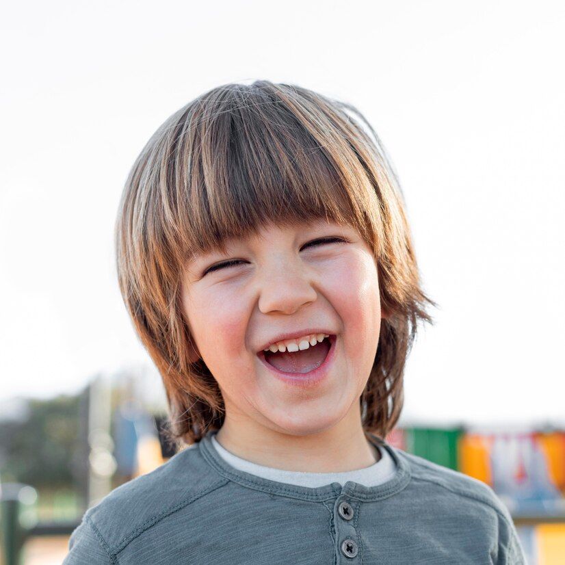 A young boy is laughing with his mouth open