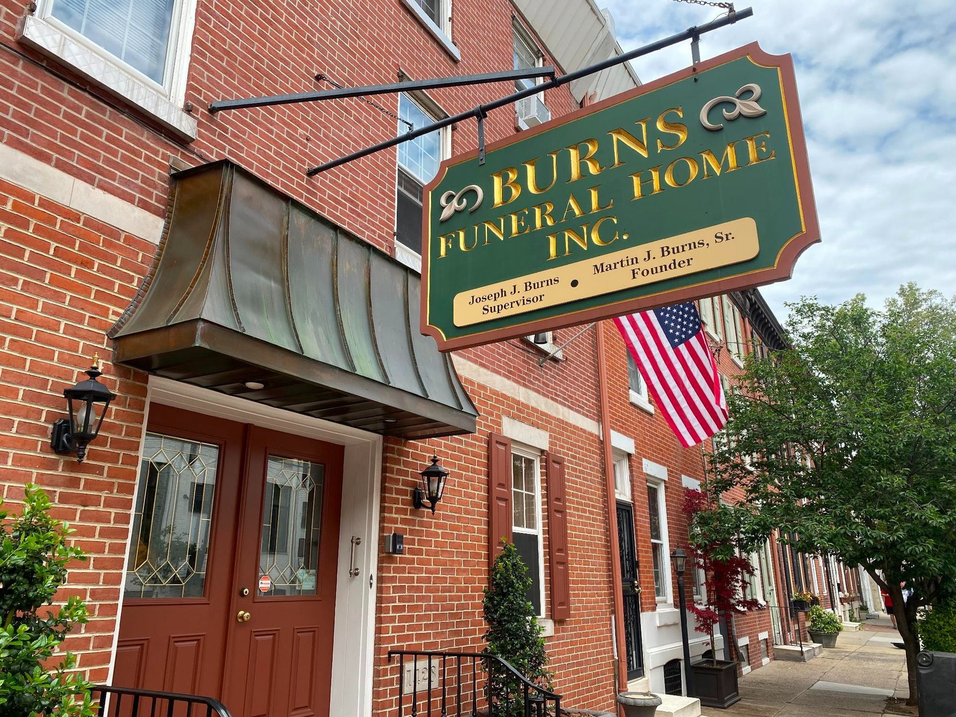 Burns Funeral Home Inc. sign on a brick building, with an American flag.