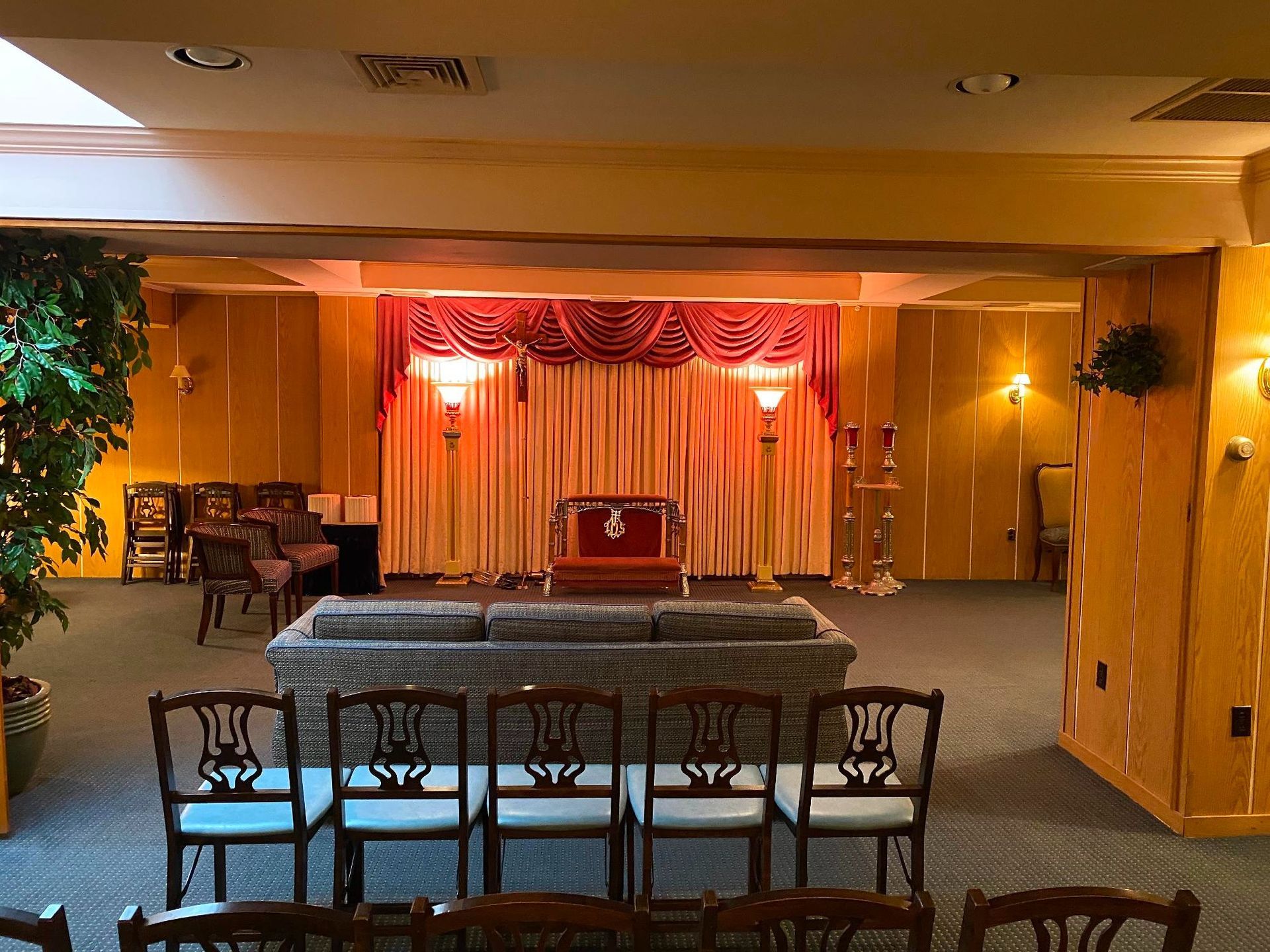 Funeral home interior with a casket, rows of chairs, and a draped altar.