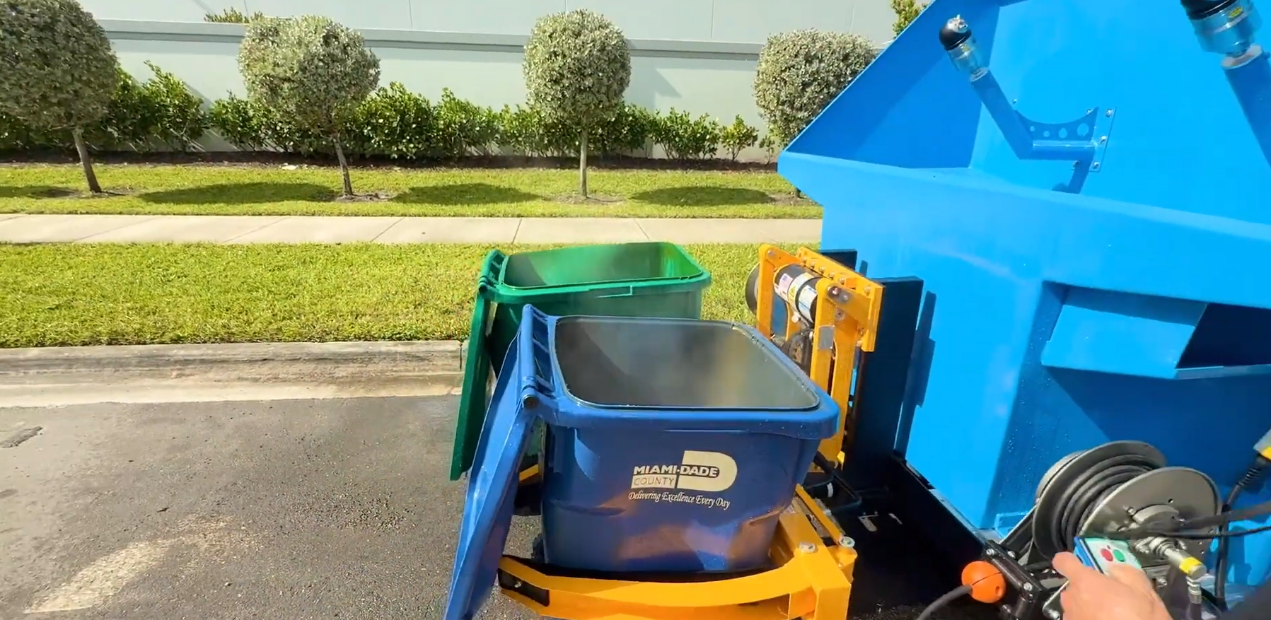 A person is holding a spray bottle over a trash can.