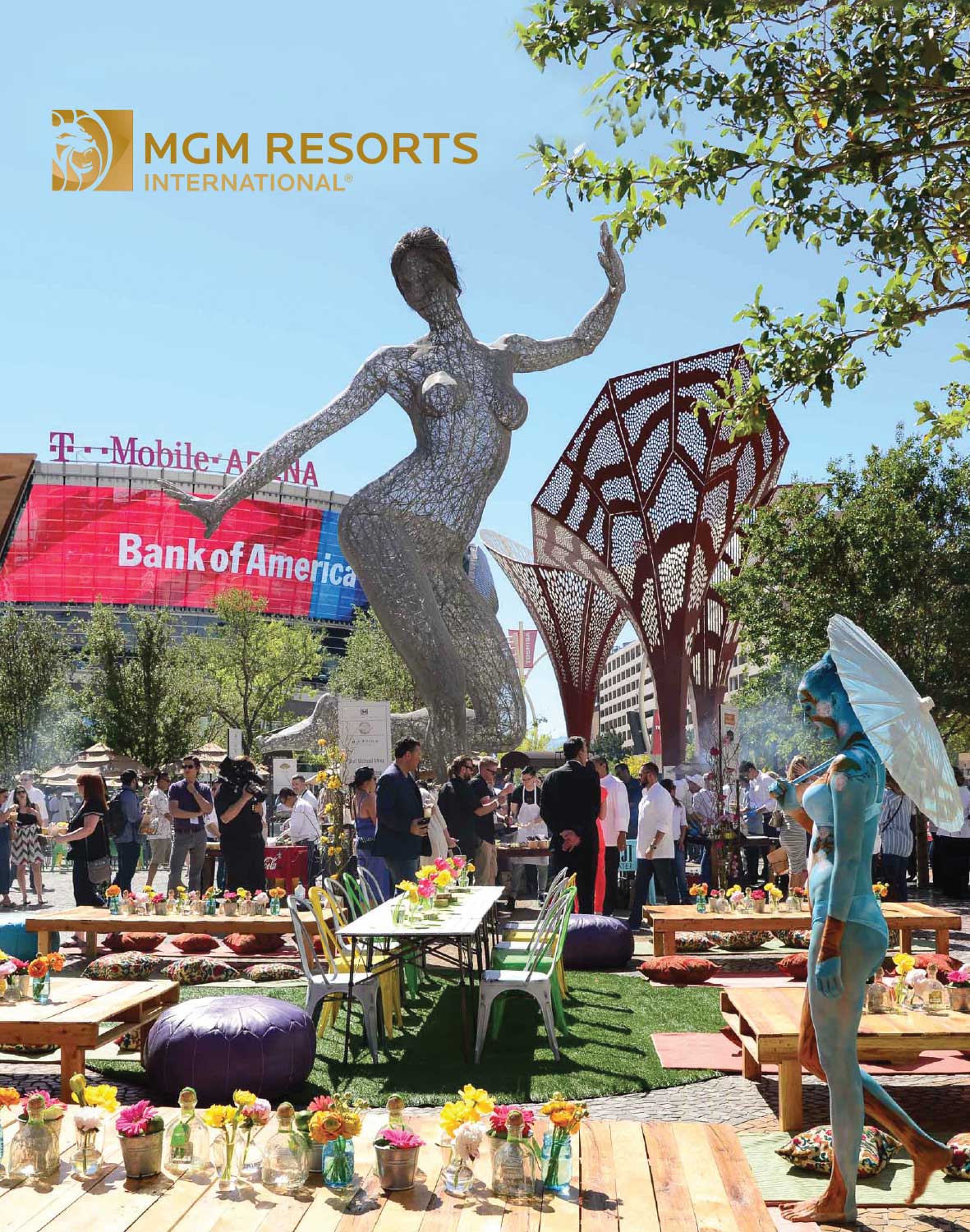Outdoor event with sculpture, people, tables, and flowers; MGM Resorts International logo in top left corner.