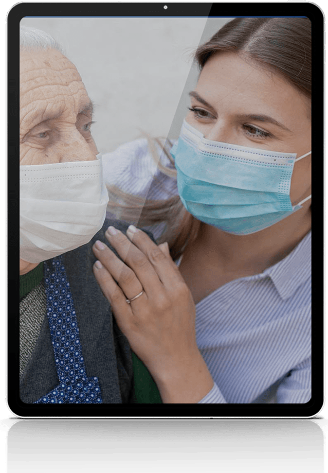 Woman comforting older person, both wearing masks.