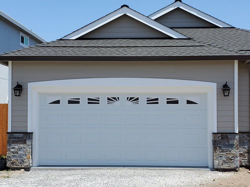 A white garage door is sitting in front of a house.