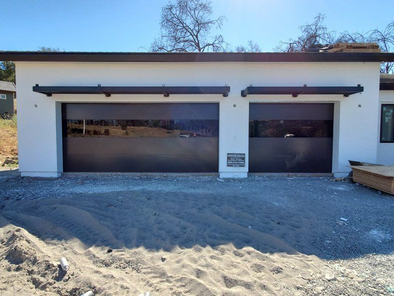 A white house with a black garage door is being built.
