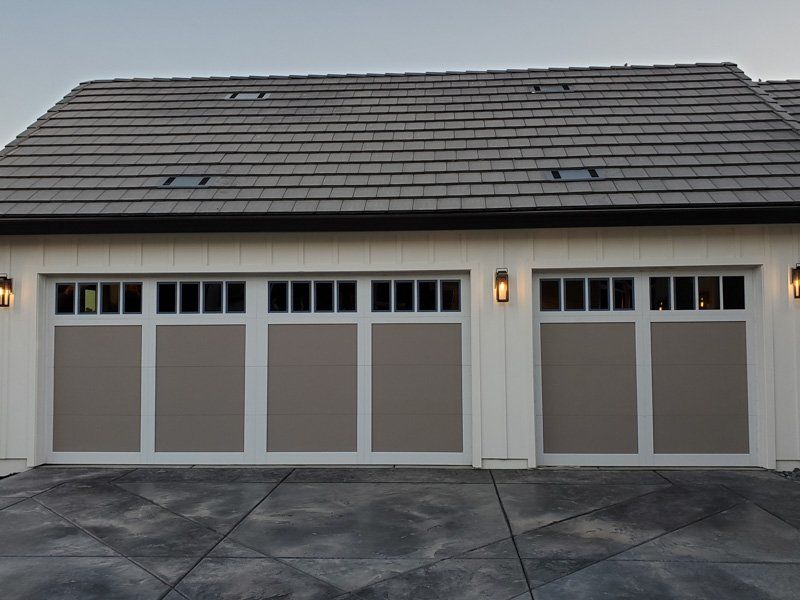 A white house with a gray garage door and a gray roof.