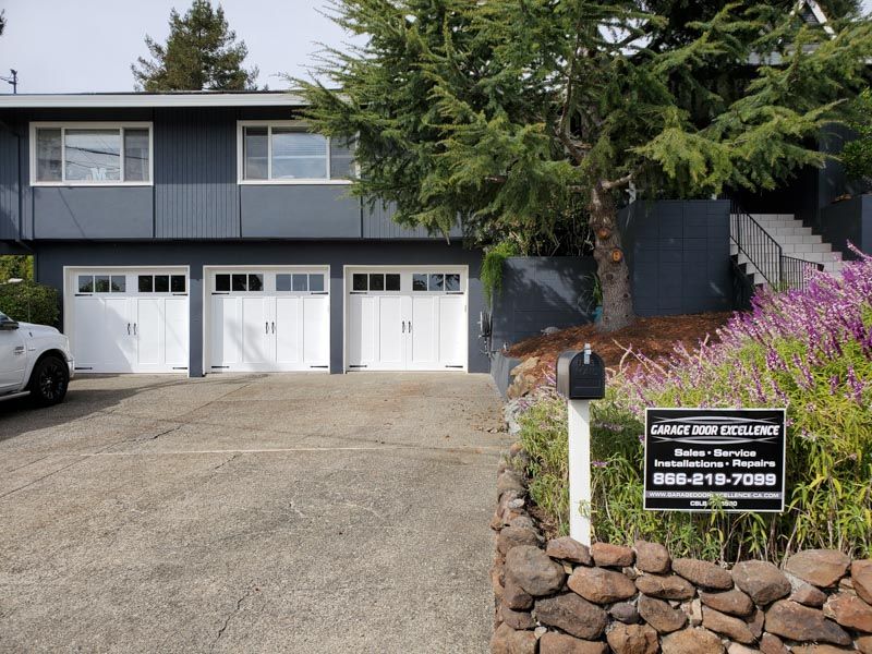 A white car is parked in front of a large house