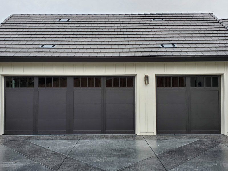 There are three garage doors on the side of a house.