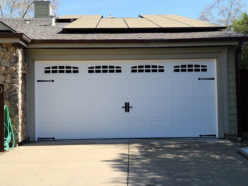 A white garage door with a solar panel on the roof