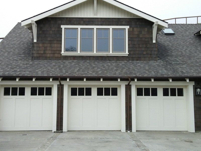 A house with three garage doors and a window on top