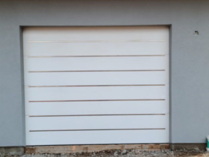 A white garage door with a gray wall behind it