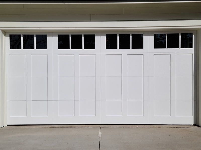 A white garage door with black windows on a house.
