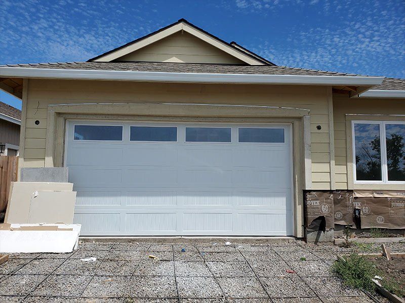 A white garage door is sitting in front of a house under construction.