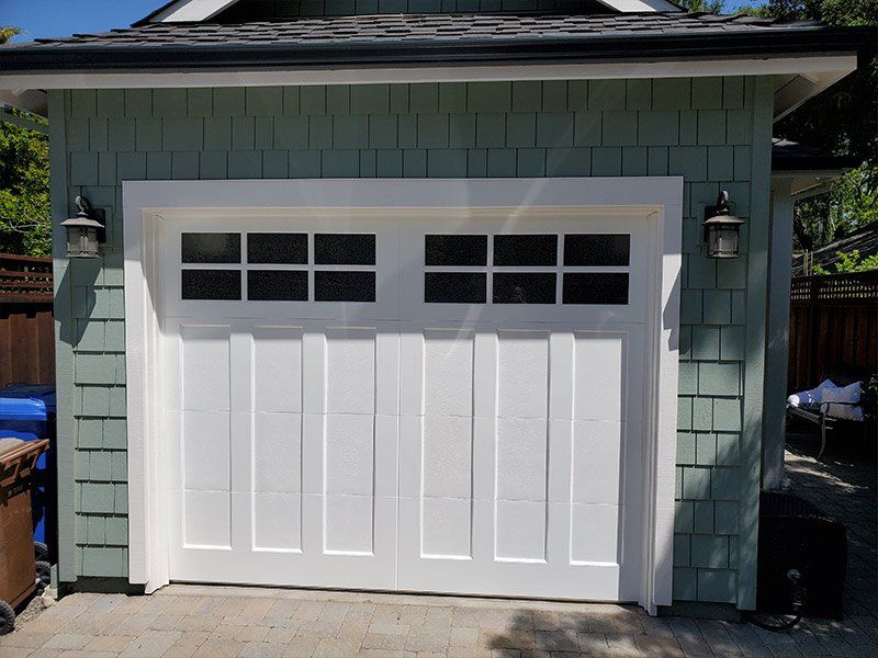 A green house with a white garage door