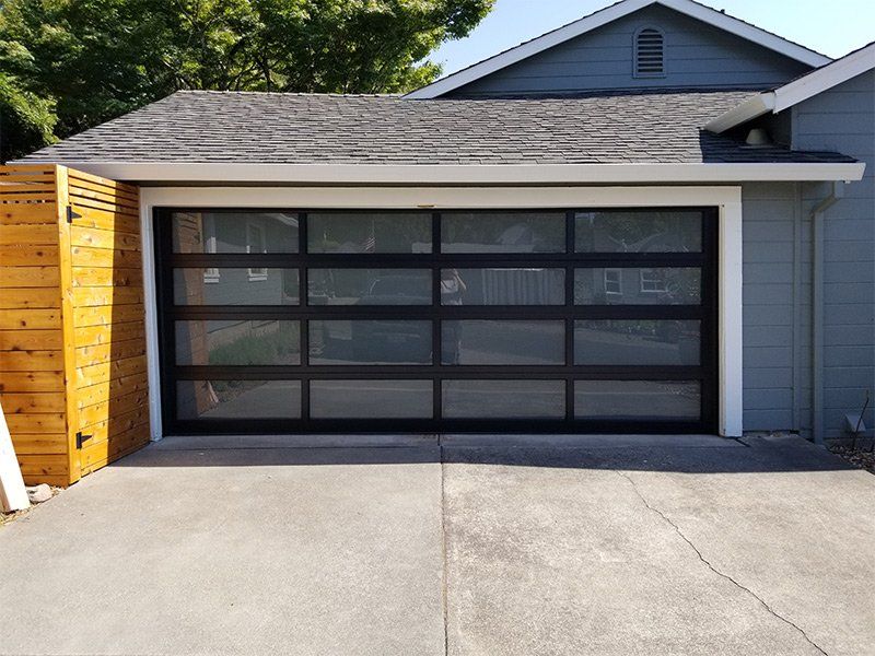 A garage with a black door and a wooden fence in front of it.