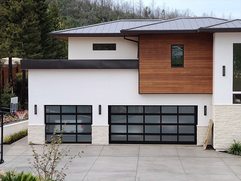 A white house with a black garage door and a car parked in front of it.