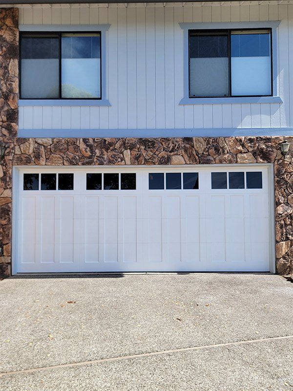 A white garage door is in front of a house