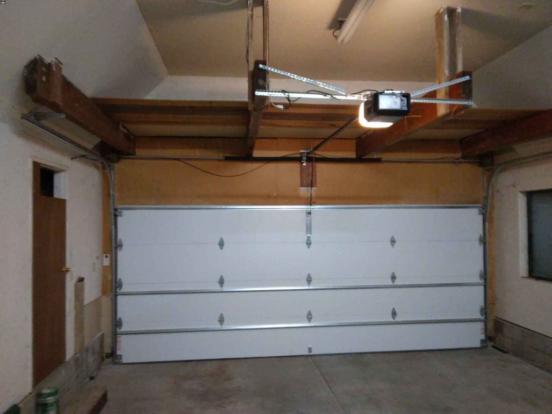 A garage with a white garage door and a garage door opener