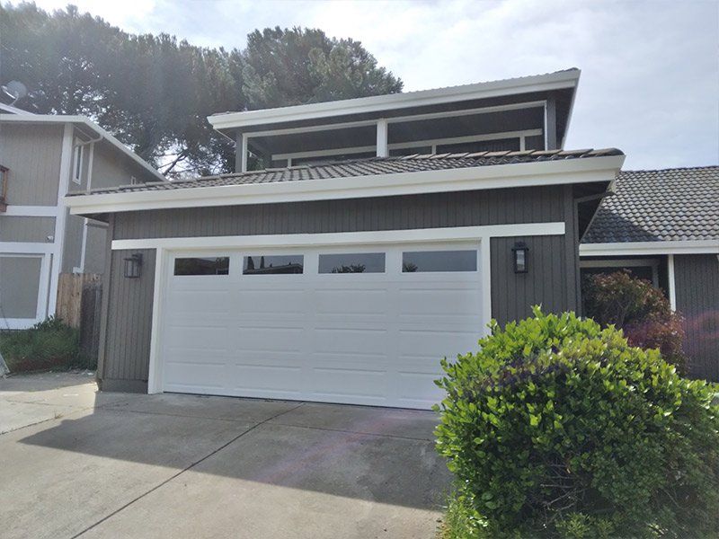 A white garage door is sitting in front of a house.
