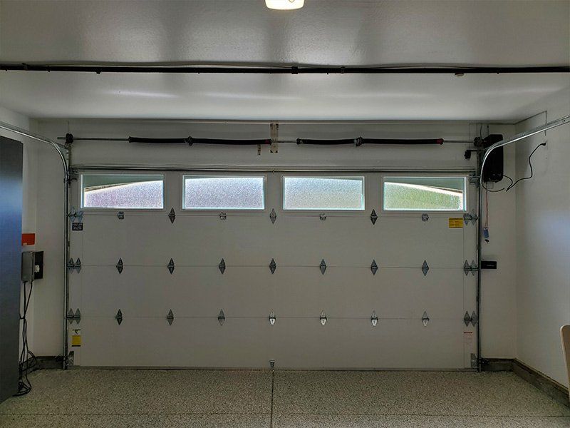 An empty garage with a white garage door and a window.