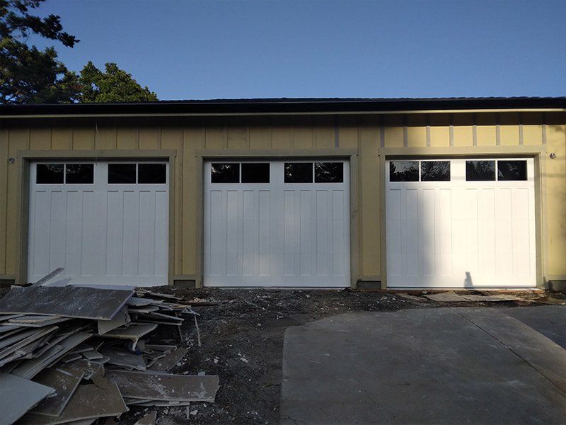 Three white garage doors on a yellow building