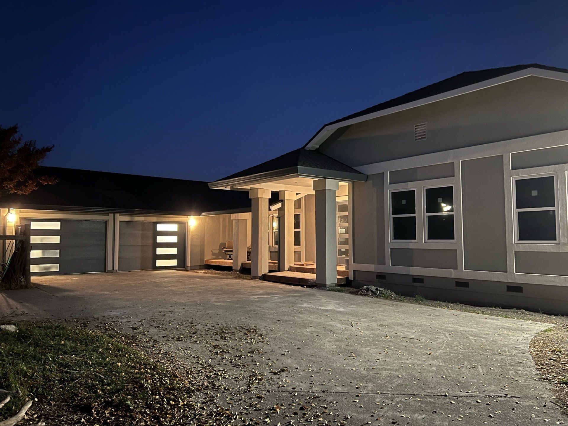 A double glass garage door installation in the Greater Bay area by Garage Door Excellence lit up at night