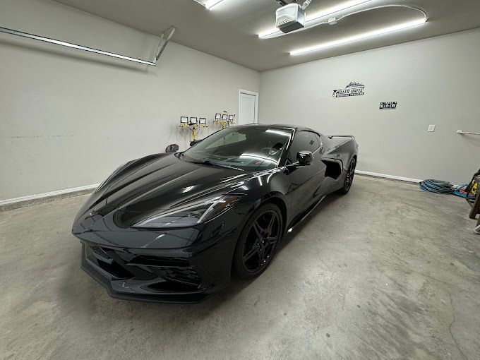 A black sports car is parked in a garage.