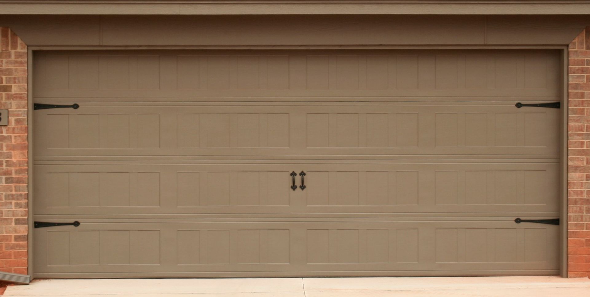 Beige double garage door on a brick house exterior