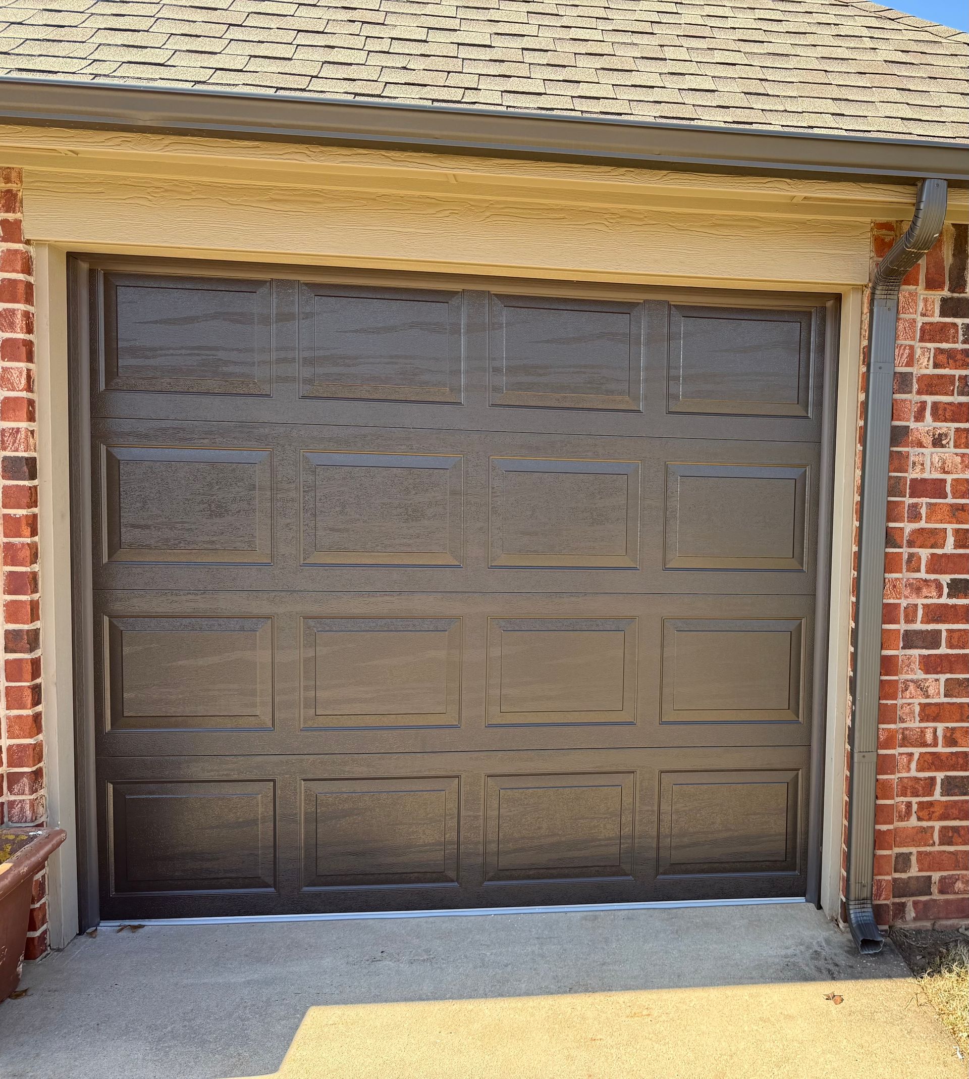 Closed brown garage door on a brick house exterior