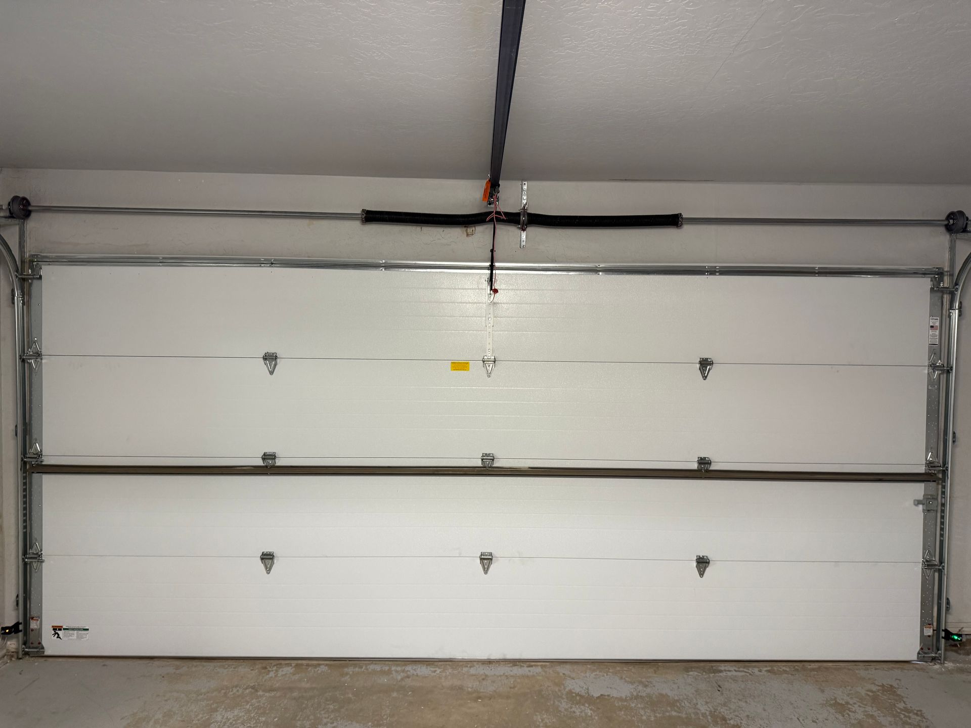 White double garage door in a garage interior with metal tracks and opener rail above