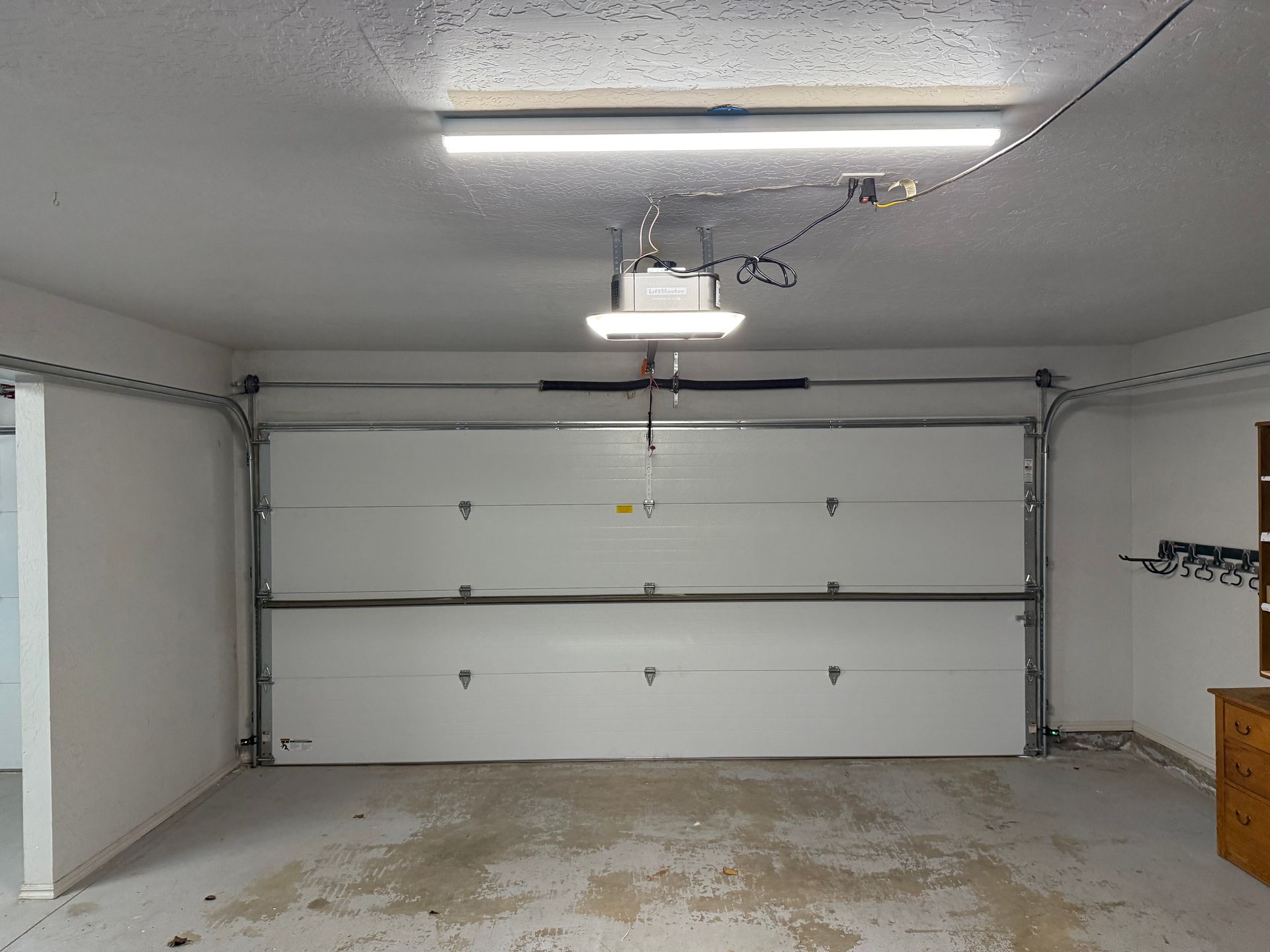 Empty white garage with closed sectional door, ceiling light, and stained concrete floor