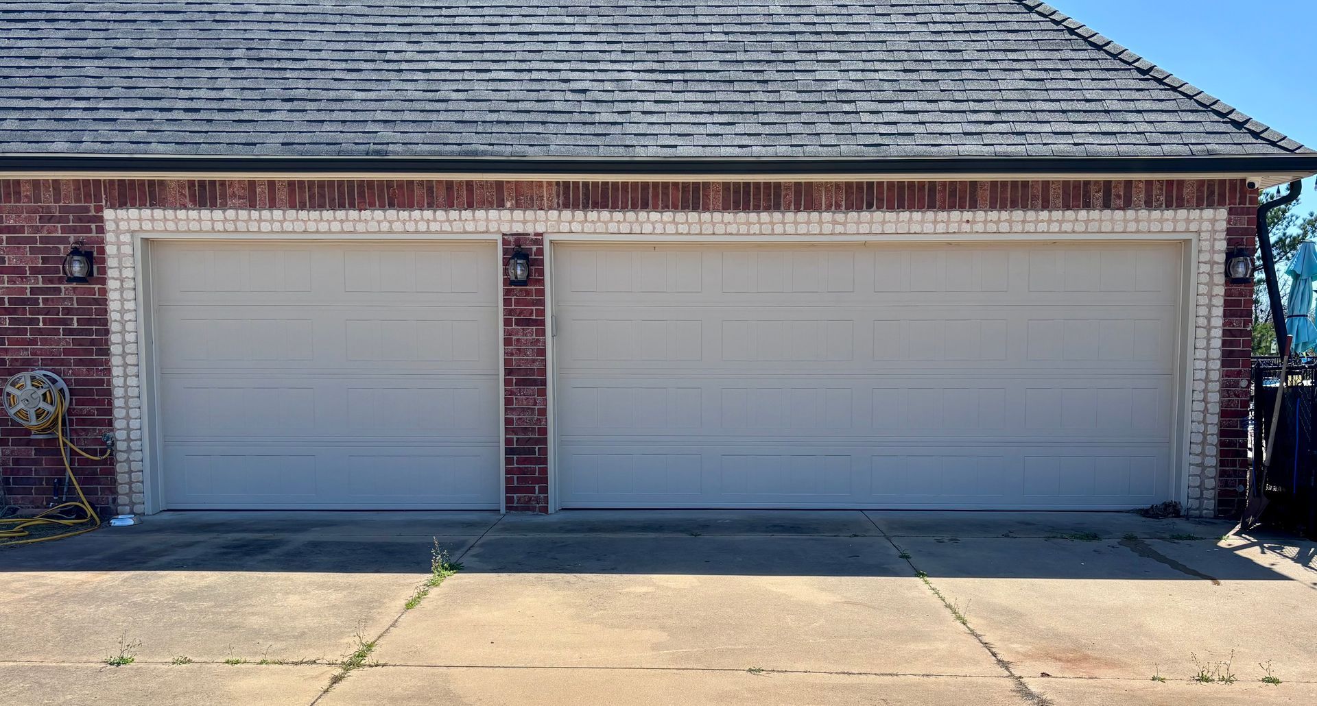 Two-car garage with closed white doors on a brick house exterior.