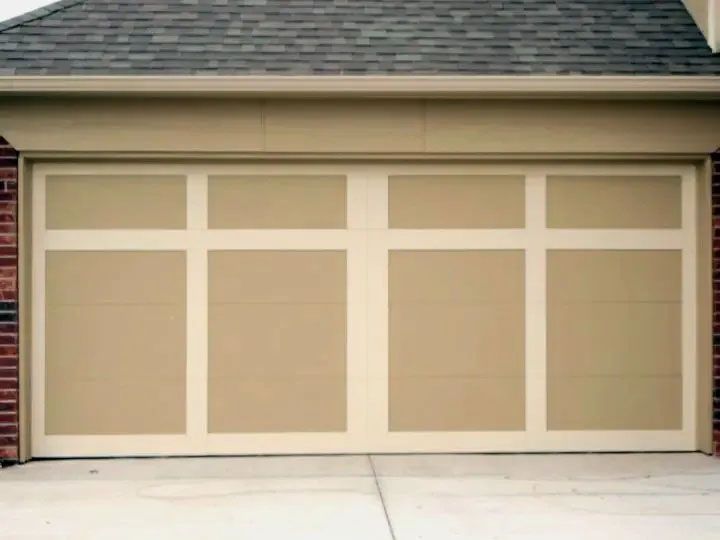 Beige double garage door with white trim on a suburban house