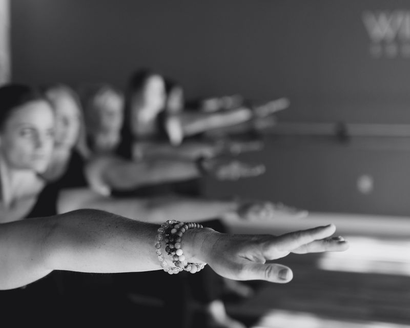 People in a group exercise class extend their arms forward in a studio.
